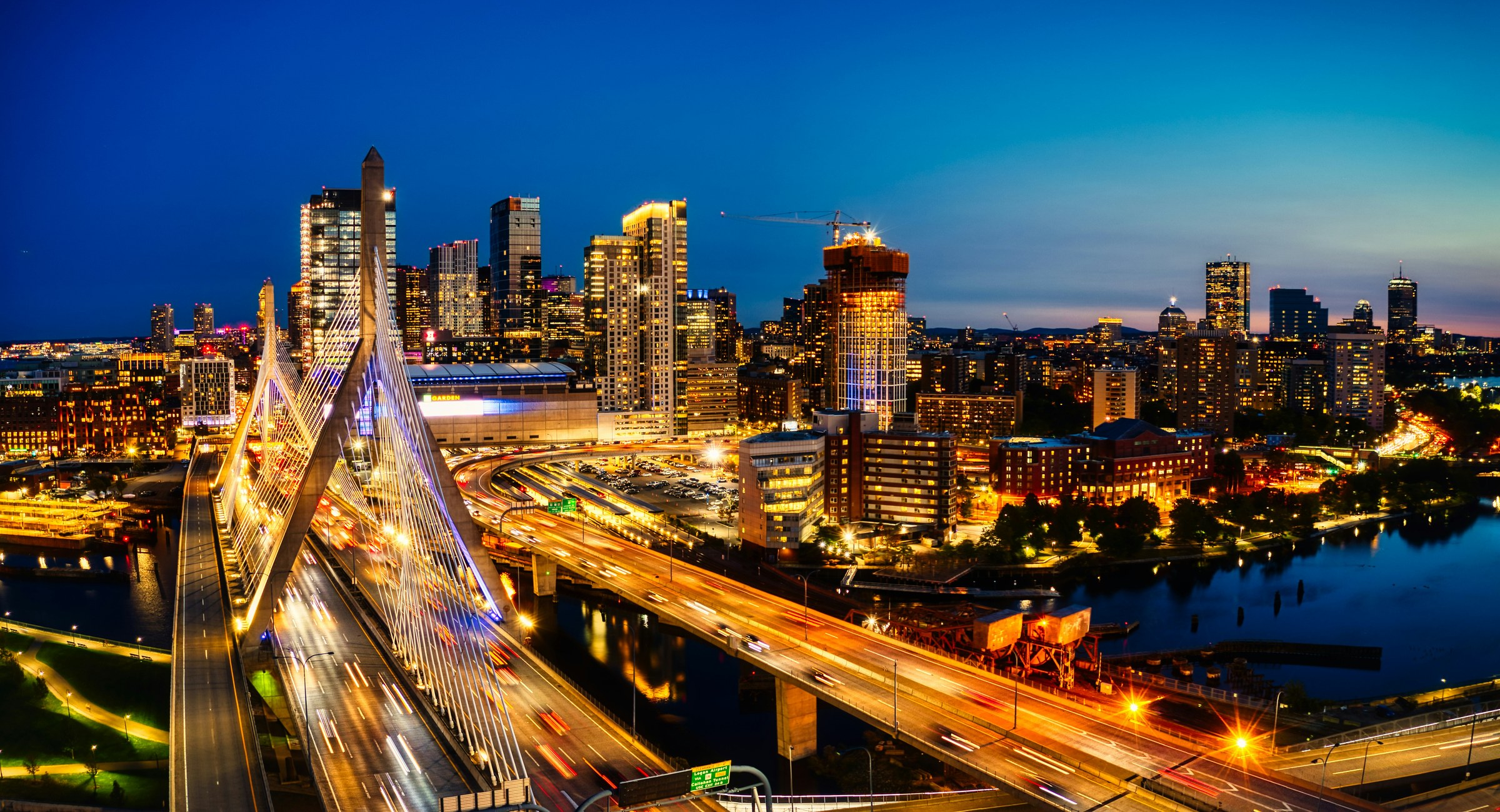 Boston skyline at night with the Zakim Bridge and a construction crane visible